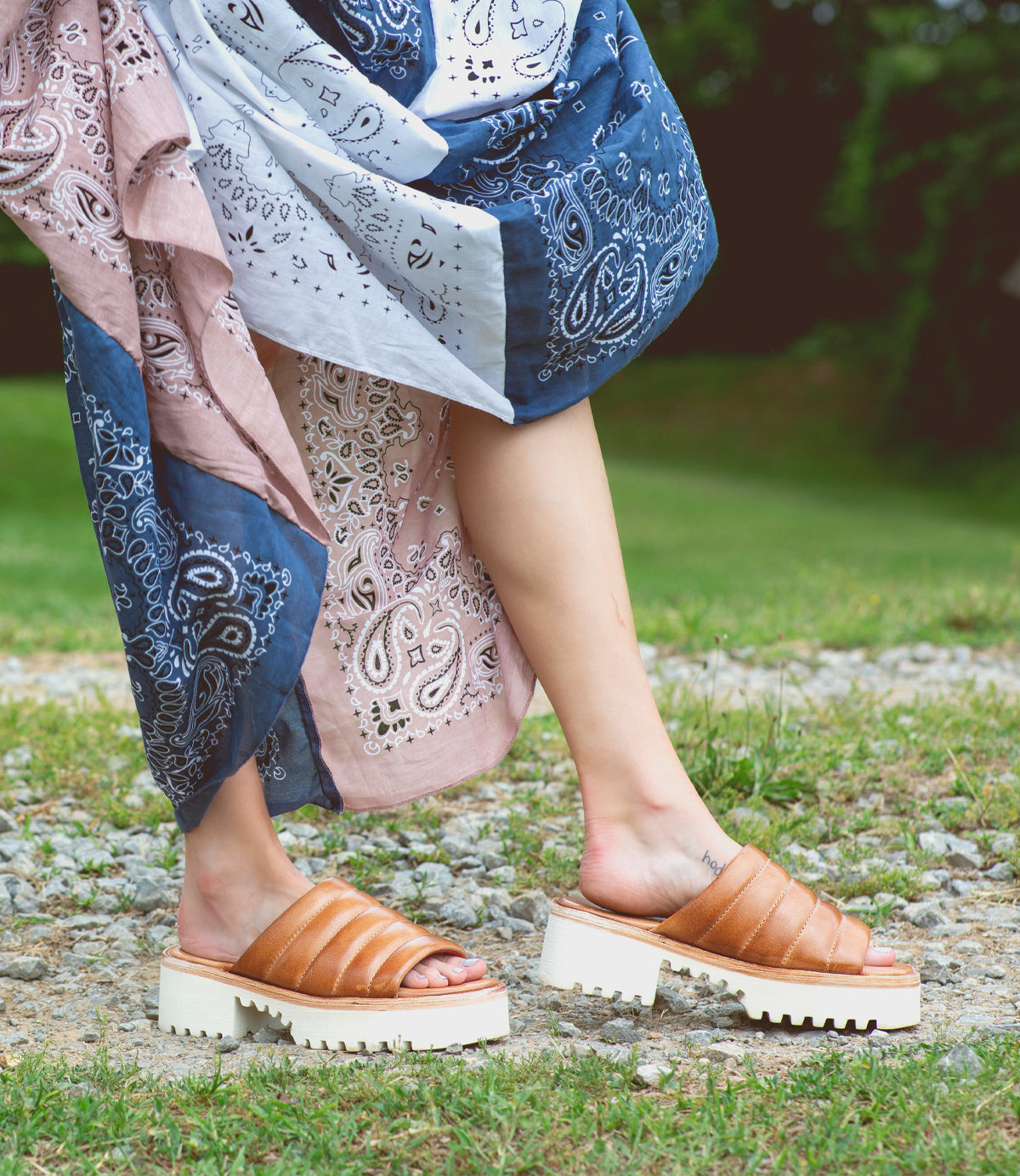 A woman wearing tan Bed Stu sandals.