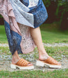 A woman wearing tan Bed Stu sandals.