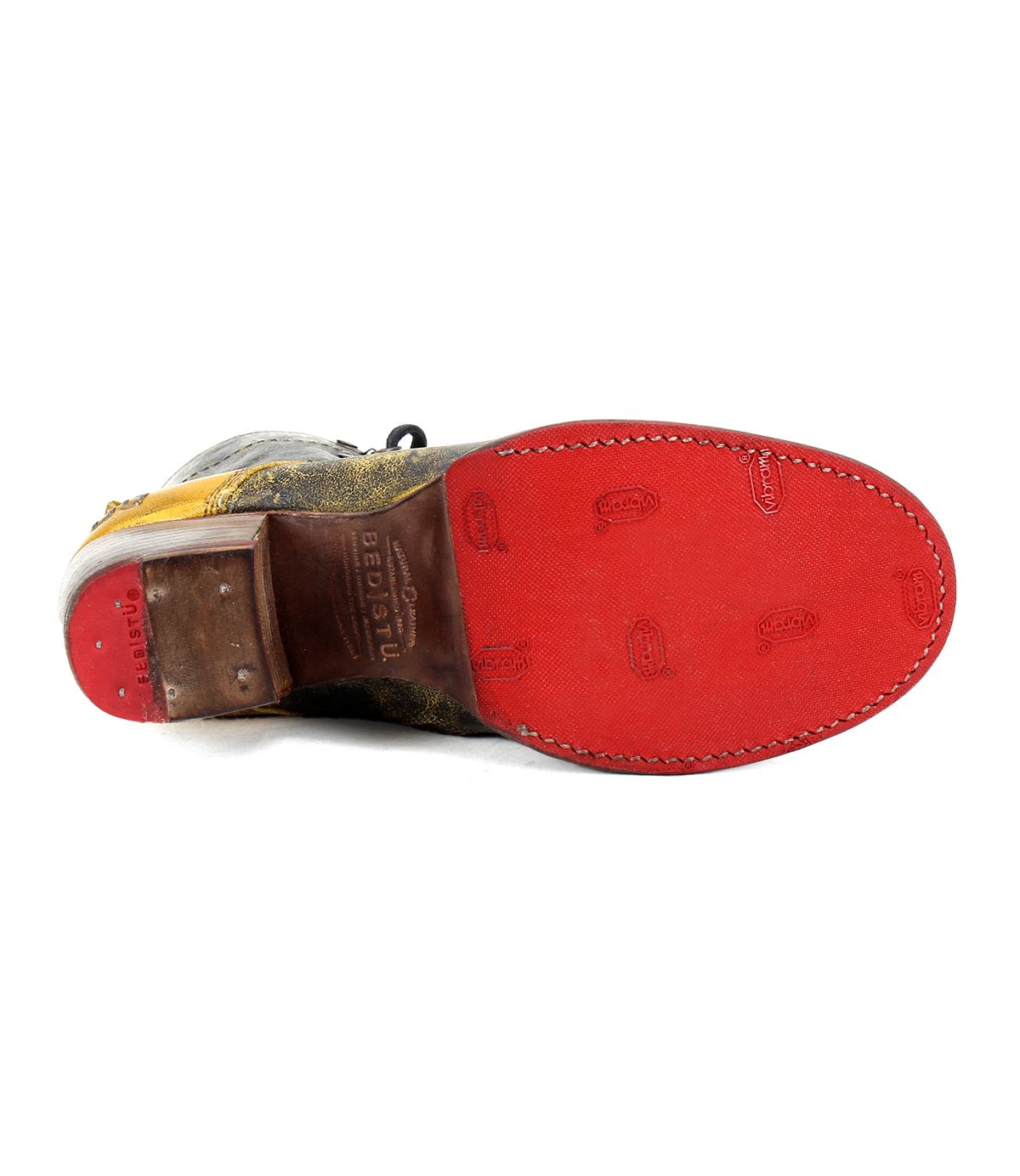 The Bed Stu Judgement leather shoe is shown from the bottom, featuring a red sole with visible branding imprints. It boasts an 8-eye lace-up design and a cushioned insole for added comfort.