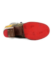The Bed Stu Judgement leather shoe is shown from the bottom, featuring a red sole with visible branding imprints. It boasts an 8-eye lace-up design and a cushioned insole for added comfort.