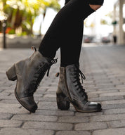 A woman wearing Bed Stu Judgment boots on a sidewalk.