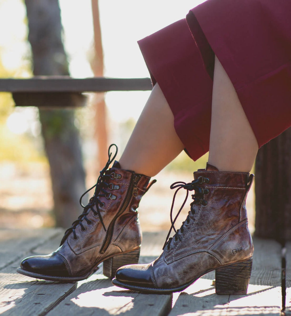 A woman wearing Bed Stu lace up boots on a wooden bench.