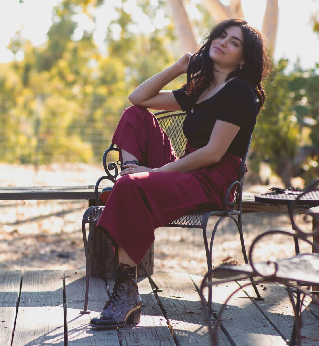 A woman sitting on a Bed Stu wooden bench.