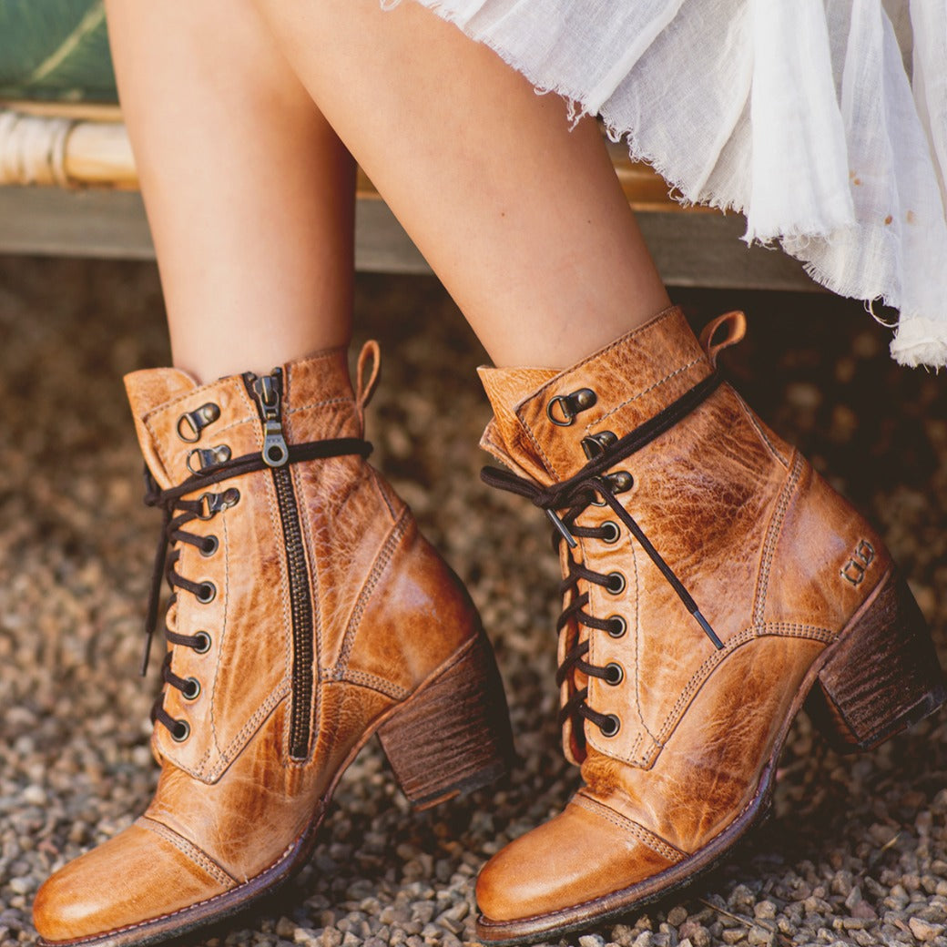 A woman's legs are sitting on a bench wearing Bed Stu Judgement boots.