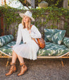 A woman in a white hat sitting on a green Judgment couch by Bed Stu.