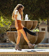 A woman walking in front of a fountain in a Bed Stu Judgement skirt.