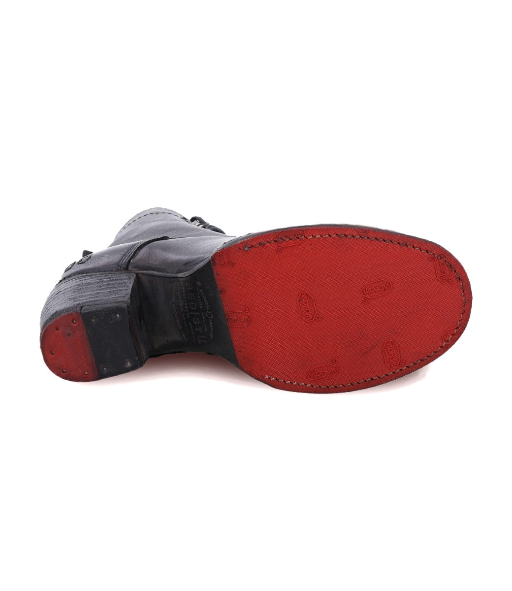 A pair of Bed Stu Judgement black shoes with red soles on a white background.