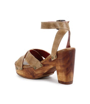 The Kalah by Bed Stu is a tan leather high-heeled sandal featuring an ankle strap, sustainably sourced materials, and a wooden sole with platform heel, shown from the back.