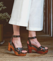 A woman wearing white pants and Bed Stu Kalah wooden sandals.