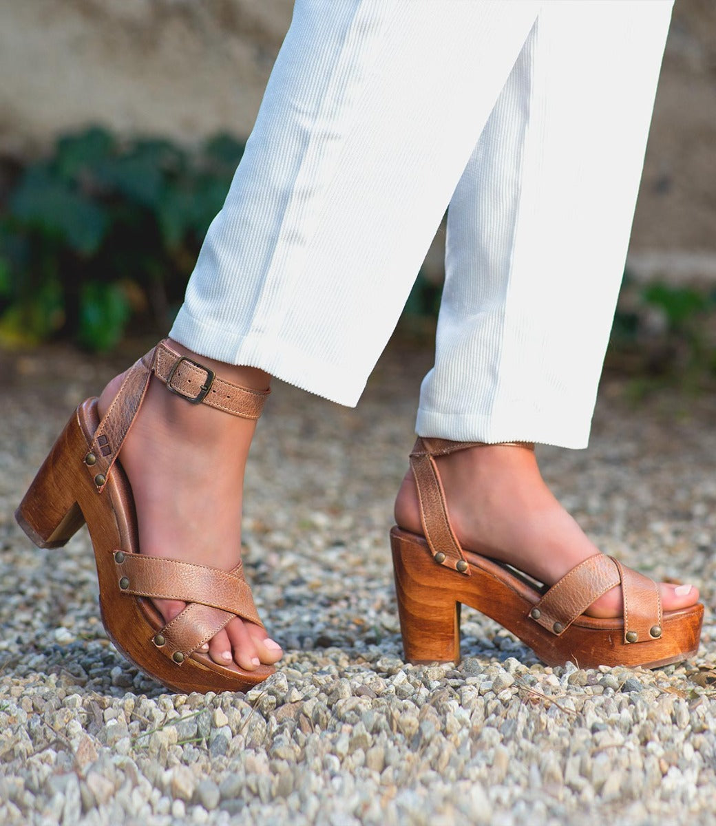 A woman wearing white pants and Bed Stu Kalah sandals.