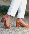 A woman wearing white pants and Bed Stu Kalah sandals.