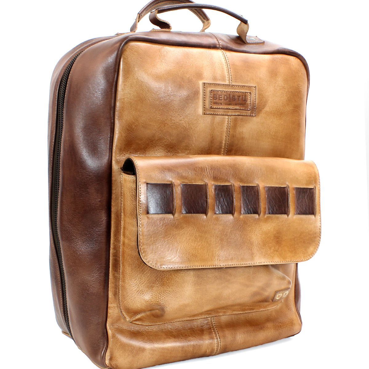 A handcrafted brown leather backpack with a large front pocket and a handle on top. The Kamet by Bed Stu, made from vegetable tanned leather, features a brand label and a zipper running around the sides.