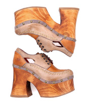 A pair of Bed Stu Karaoke stacked, tan leather platform shoes featuring chunky wooden heels and decorative metal studs, evoking a vibrant 70s era aesthetic.