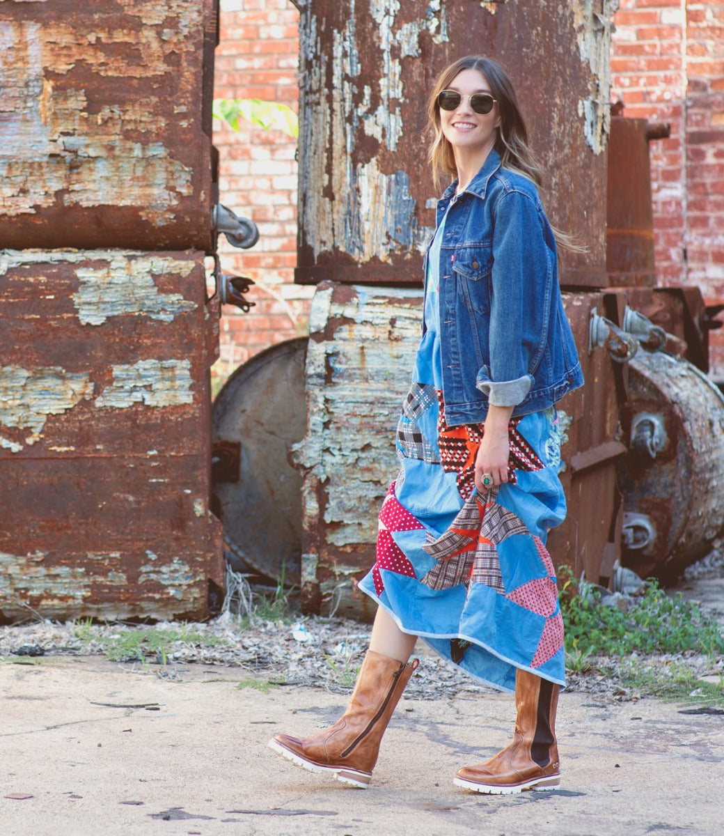 A woman wearing a denim jacket, denim skirt, and Kataleya boots by Bed Stu.