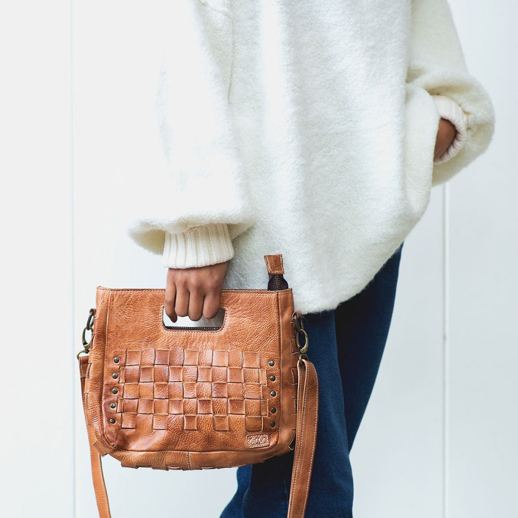 A woman wearing a sweater and jeans holding a Keiki purse by Bed Stu.