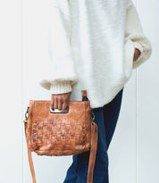 A woman wearing a sweater and jeans holding a Keiki purse by Bed Stu.