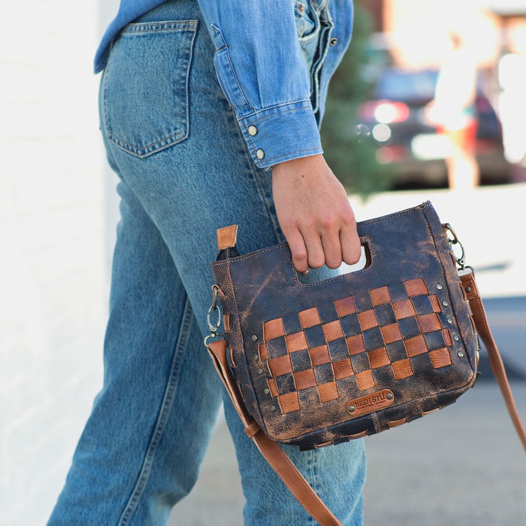 A woman wearing blue jeans and a Bed Stu Keiki checkered purse.