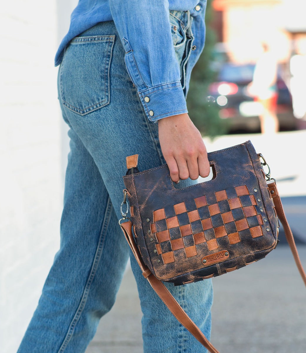 A woman wearing blue jeans and a Bed Stu Keiki checkered purse.