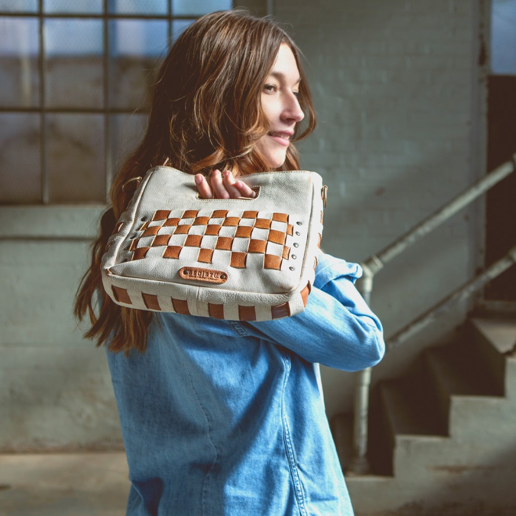 A woman holding a Keiki bag with a checkered pattern. (Brand: Bed Stu)