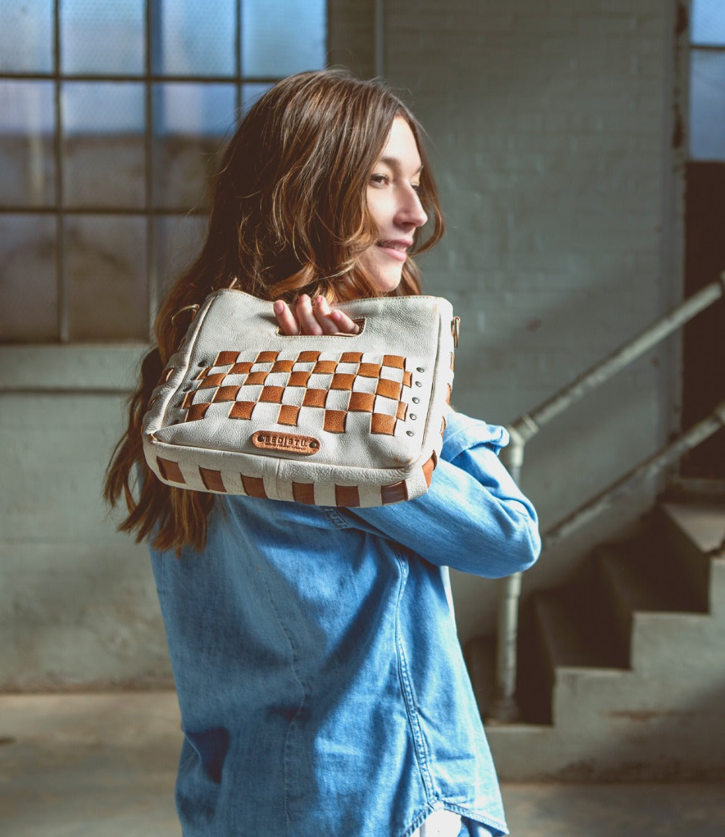A woman holding a Keiki bag with a checkered pattern. (Brand: Bed Stu)