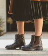 A woman wearing Kiefra by Bed Stu brown leather boots and a pleated skirt.