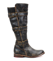 A side view of the Bed Stu Kitty boot, a black, knee-high leather design featuring four decorative adjustable straps and buckles along its length and a low wooden heel.