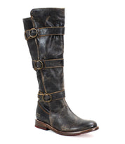 A tall beauty, the Bed Stu Kitty single worn black leather knee-high boot showcases a distressed finish with edgy sophistication, featuring three adjustable buckles for a customizable fit along the shaft and a low wooden heel.