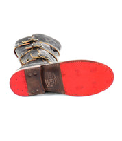 A Bed Stu Kitty boot lies on its side, spotlighting a bright red sole with textured patterns and multiple adjustable straps around the upper part.