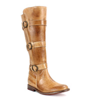 The Kitty boot by Bed Stu, a single tall beauty crafted from brown leather with three buckle straps, is displayed against a white background, exuding edgy sophistication and offering a customizable fit.
