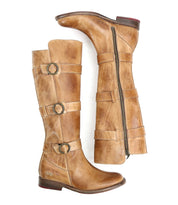 A pair of Bed Stu Kitty tan knee-high leather boots with three buckle straps and side zippers, exuding edgy sophistication and customizable fit, displayed in an upright and side position.