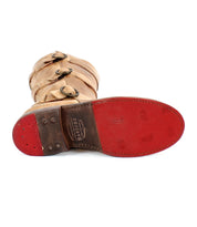 The Bed Stu Kitty boot exudes edgy sophistication with its rich brown leather and trio of side buckles. The striking red sole and branded detailing add a unique flair, while the customizable fit ensures both style and comfort.