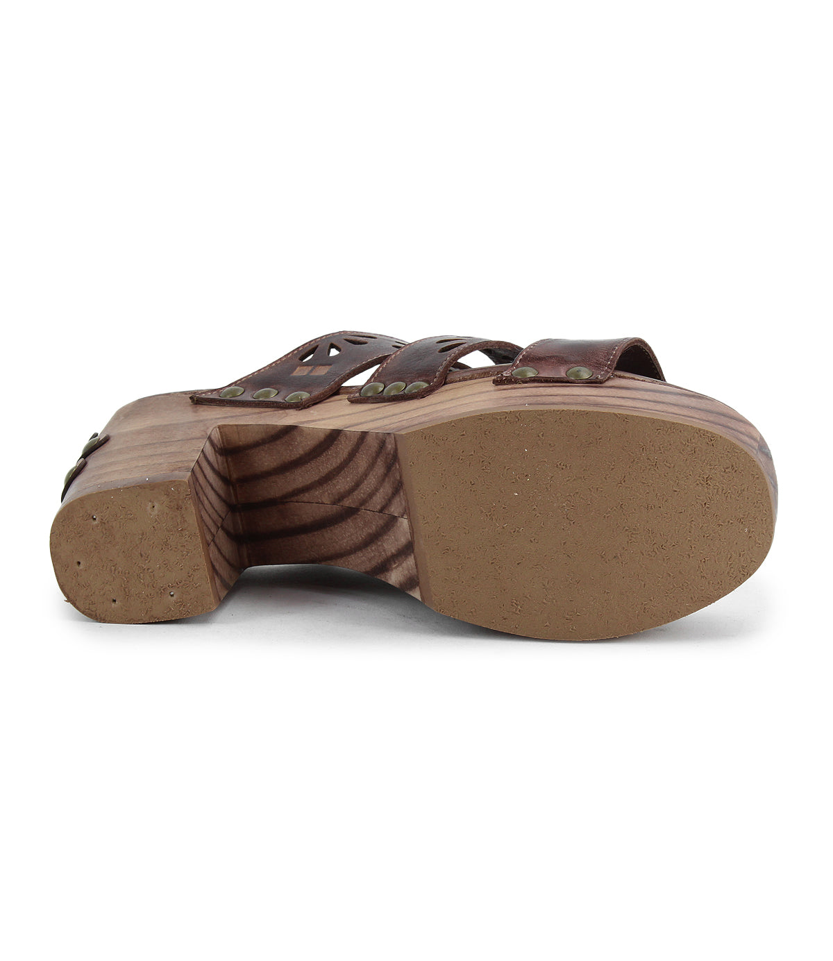 The Kreep by Bed Stu is a 70's-inspired sandal with brown leather straps and natural wooden heels. It features intricate nail and rivet details, while delicate floral cutouts seen from the side enhance its timeless design.