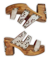 The Kreep by Bed Stu are wooden platform sandals with a 70's-inspired flair, featuring floral cutouts, stud details, a chunky wooden heel, and back embellishments for a retro vibe.
