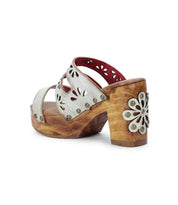Embrace a retro look with Bed Stu's Kreep sandals, featuring 70s-inspired wooden platforms and white leather straps with floral cutouts and metal studs. The wooden heel enhances the vintage vibe, complete with an intricate floral design.