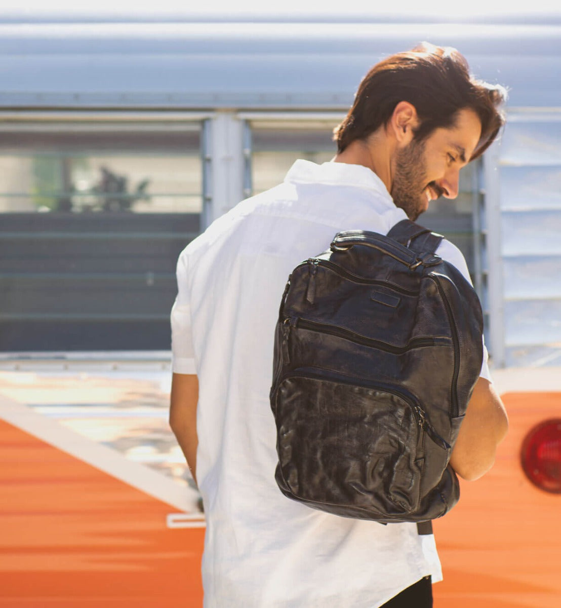 A man with a Bed Stu backpack in front of a camper van.