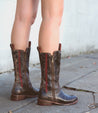 A woman wearing a pair of brown Bed Stu Latifah cowboy boots.