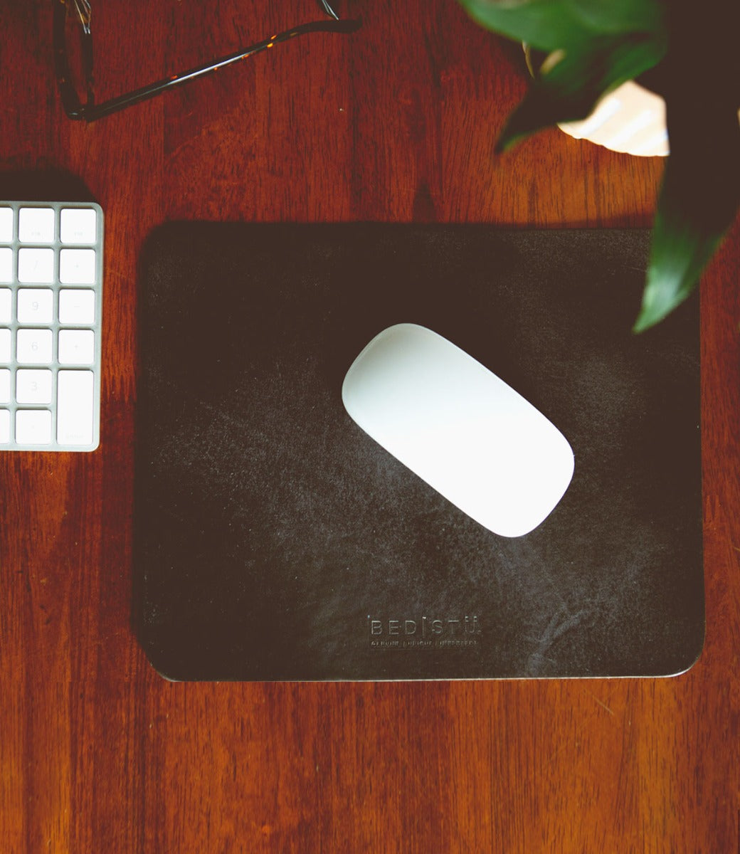 A black Launcher mouse pad on a wooden desk. (Brand Name: Bed Stu)