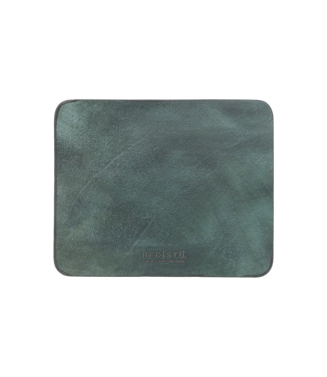 A dark green leather placemat with a smooth surface, rectangular in shape, featuring a suede underside and the brand name "Bed Stu" embossed at the bottom center. Perfect for adding elegance to your curated workspace.