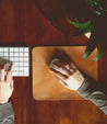 A woman typing on a Bed Stu Launcher on a wooden desk.