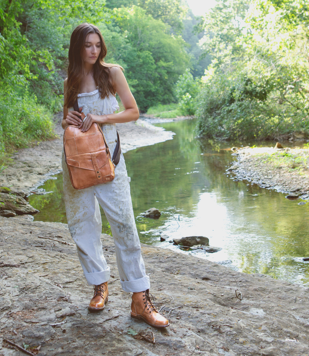 A woman is standing on a rock next to a river wearing Laurel by Bed Stu.