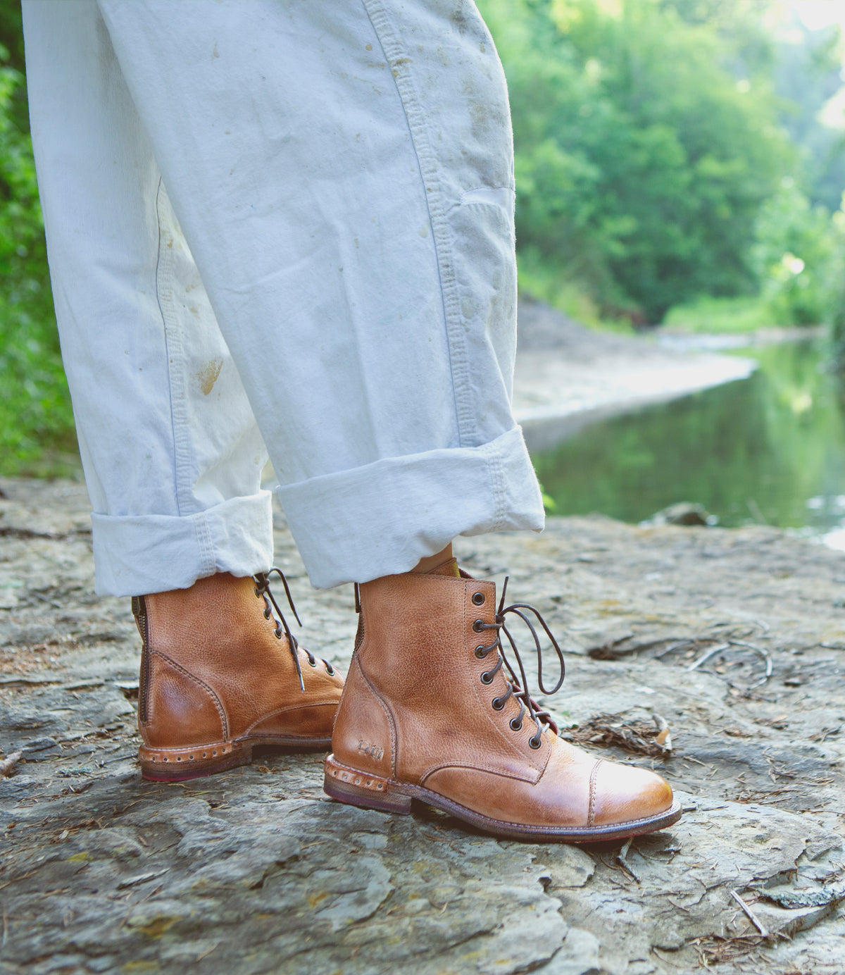 A person standing on a Laurel rock next to a river. (Brand: Bed Stu)