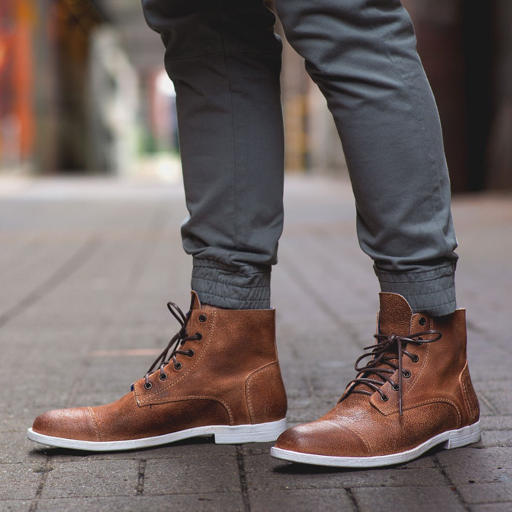A man wearing a pair of Bed Stu Leonardo brown leather boots.