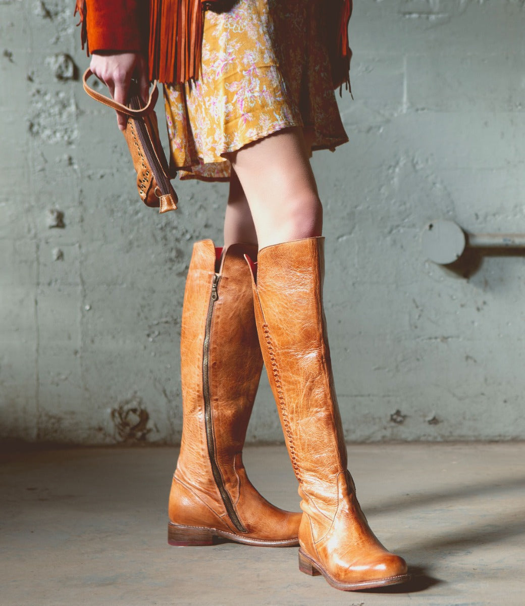 A woman wearing Bed Stu Letizia tan leather boots and a purse.