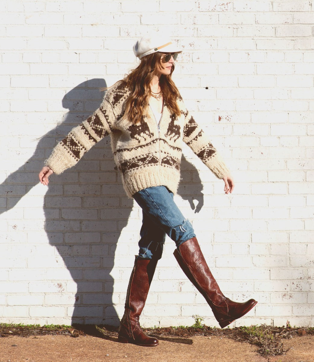 A woman wearing a sweater and Bed Stu Letizia boots in front of a brick wall.