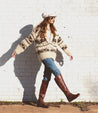 A woman wearing a sweater and Bed Stu Letizia boots in front of a brick wall.
