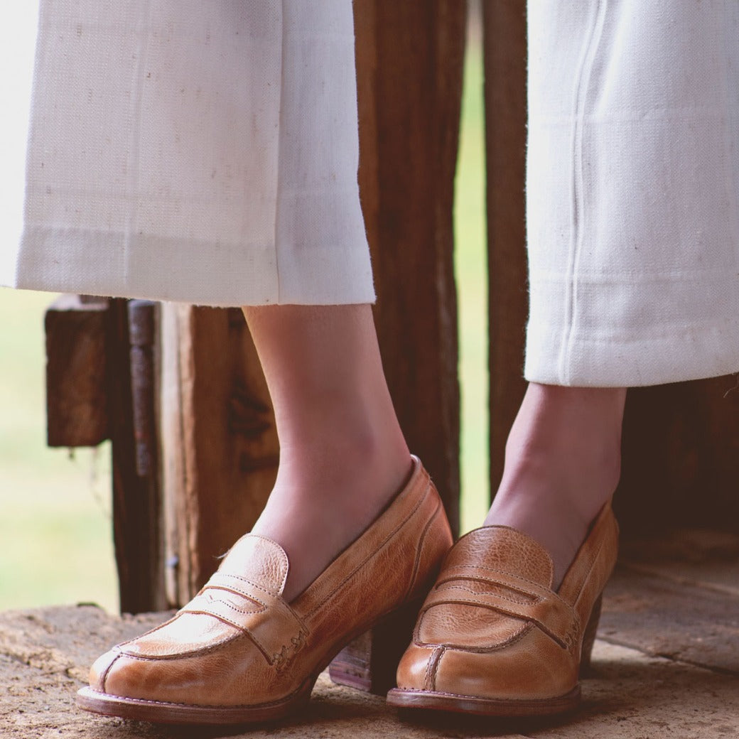A woman wearing a pair of Bed Stu Liberty loafers on a wooden floor.