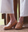 A woman wearing a pair of Bed Stu Liberty loafers on a wooden floor.