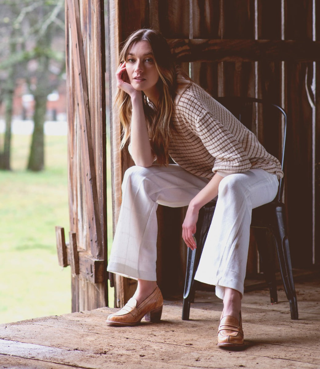 A woman sitting on a Liberty chair in a barn, made by Bed Stu.