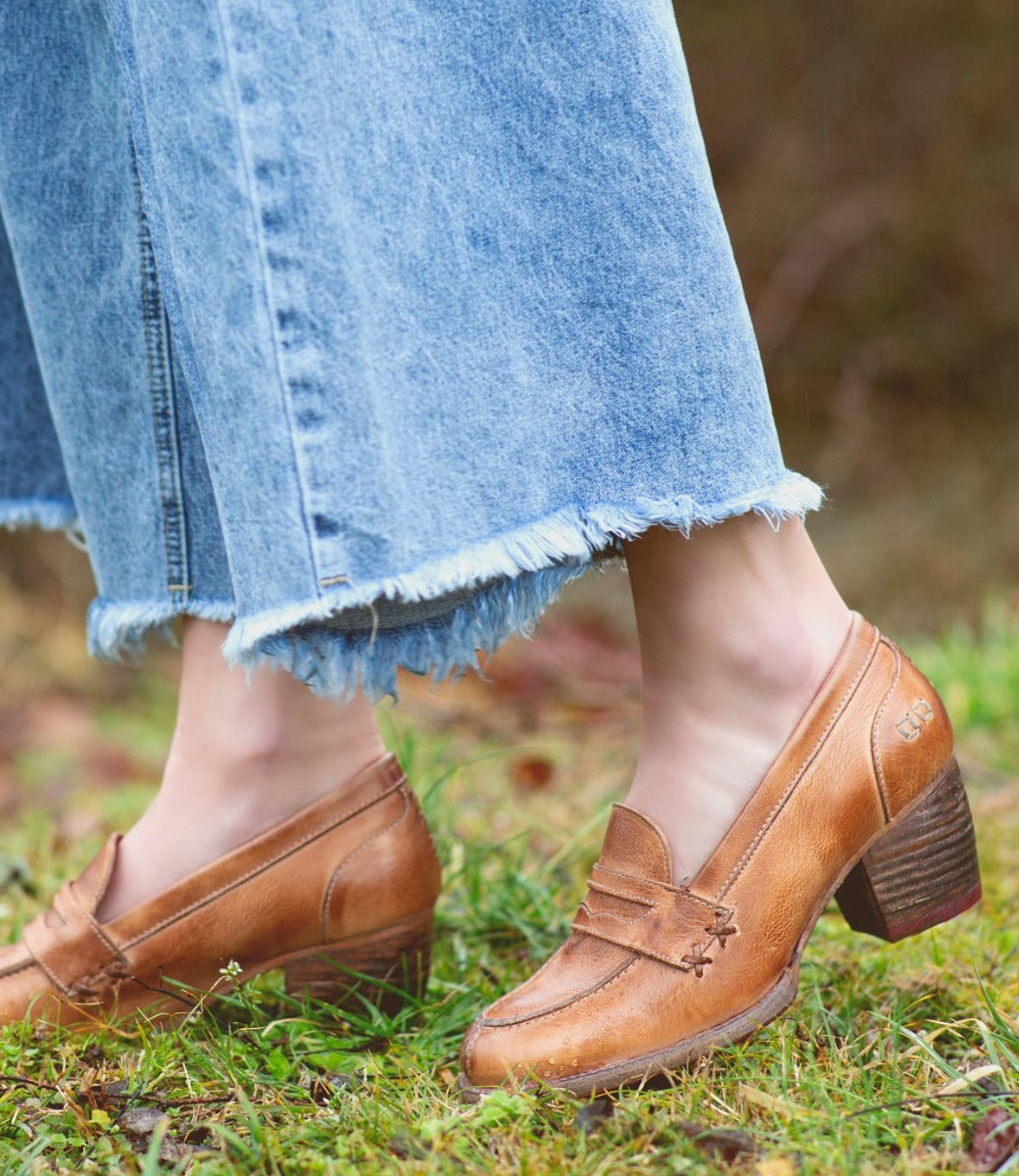 A woman wearing denim jeans and a pair of brown Bed Stu Liberty loafers.