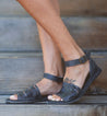 A woman wearing a pair of Bed Stu Lilia sandals on stairs.